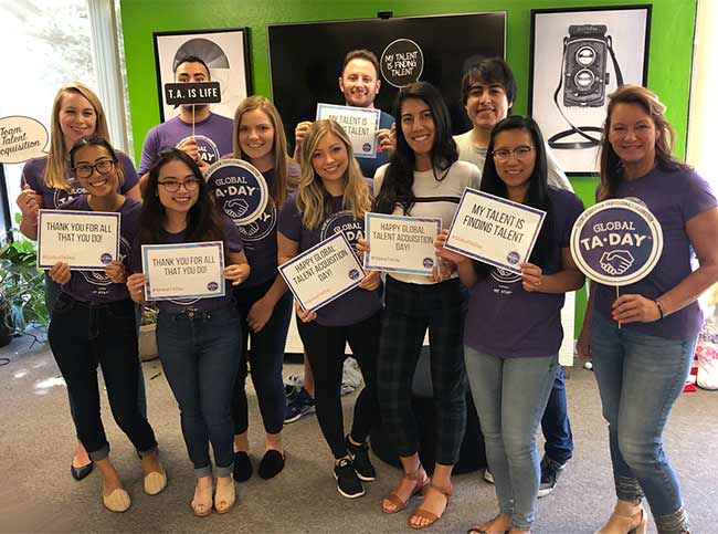 Recruitics employees standing in a group holding signs