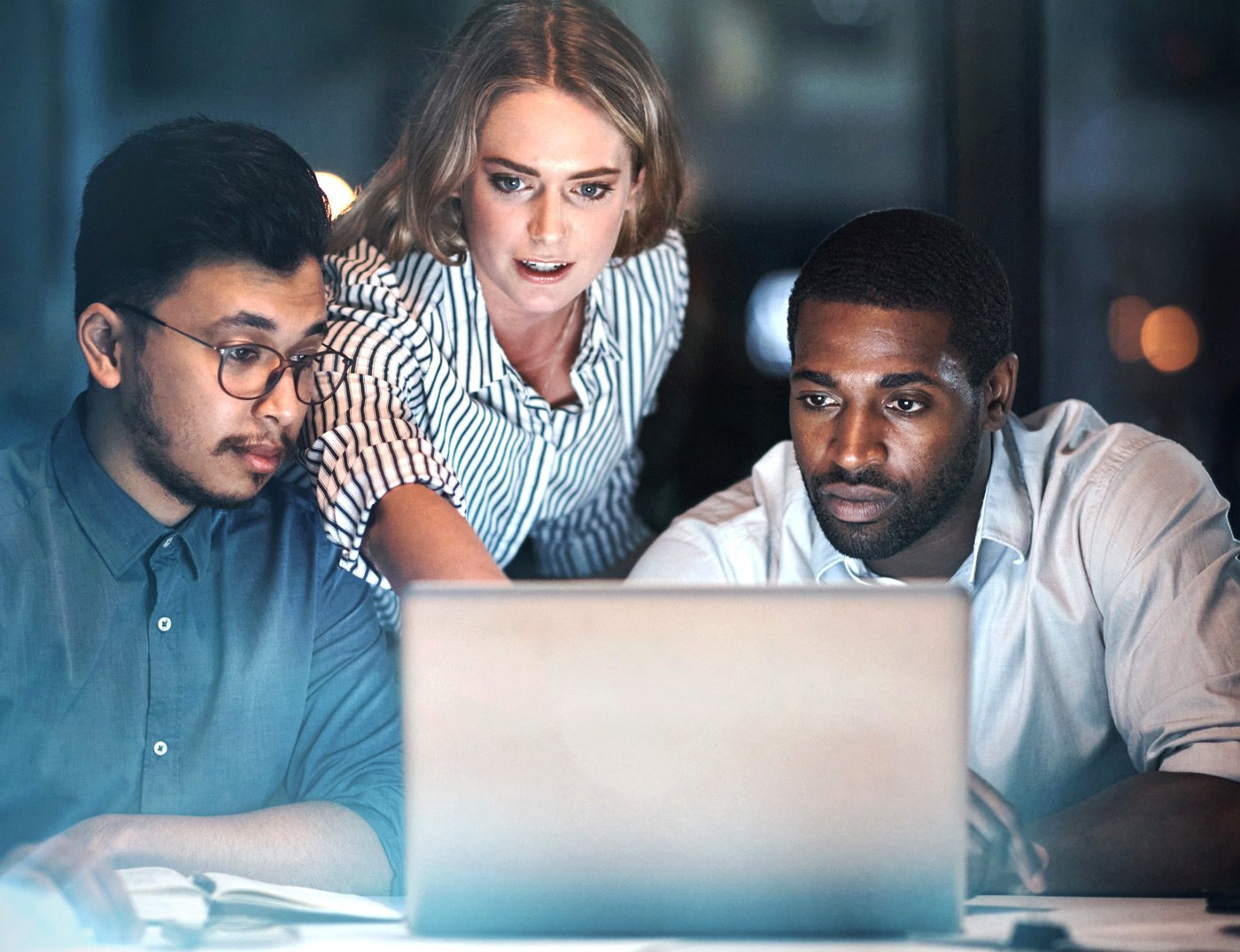 Three employees working on a laptop 