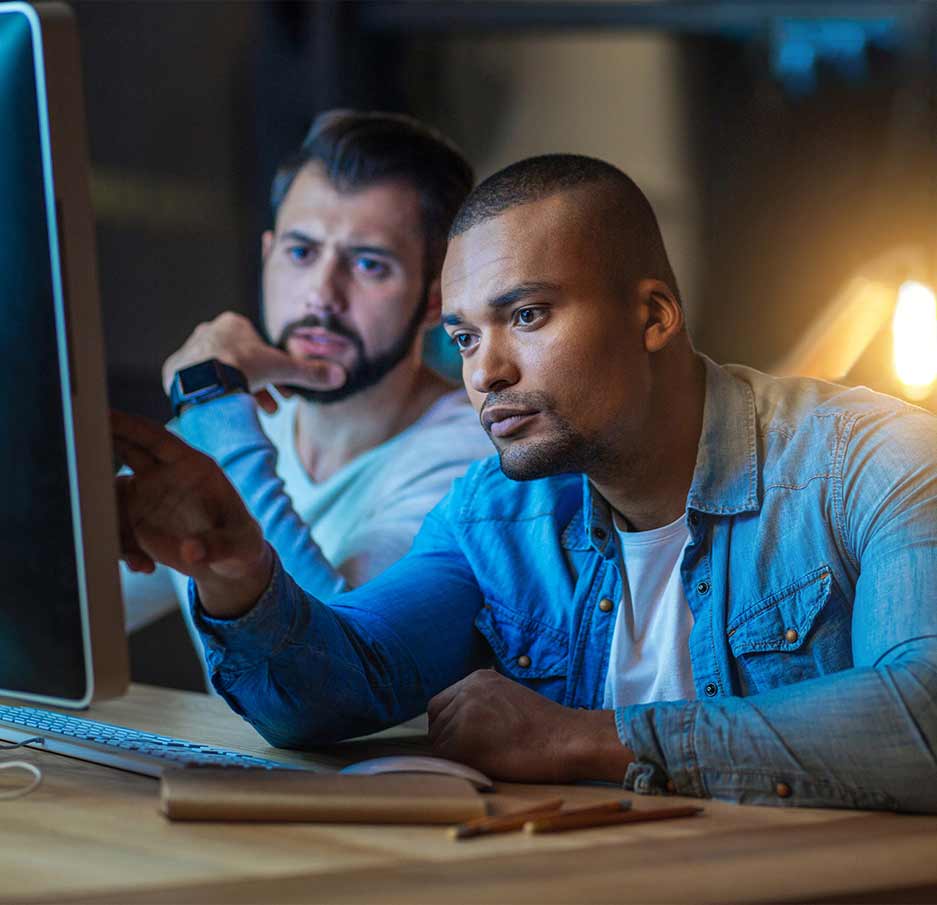 Two employees analyze data on an office computer