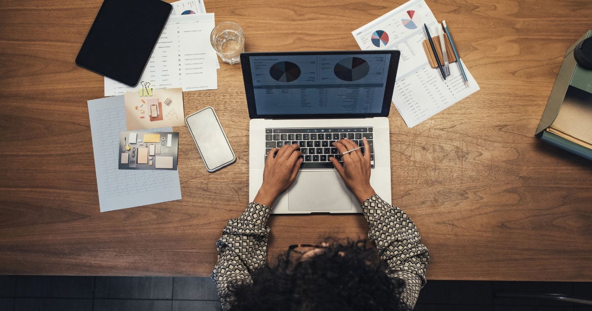 Aerial view of person working on a laptop surrounded by paperwork